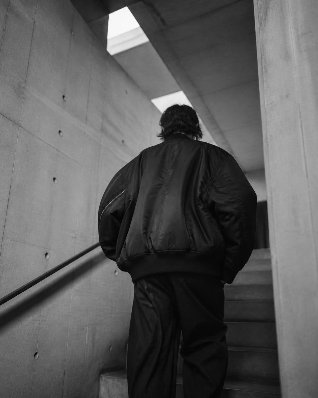 Back view of an oversized jacket in a concrete stairwell